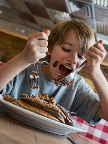 young boy eating pancakes at Frizzle Chicken Farmhouse Cafe